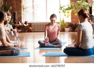 Fitness, Sport And Healthy Lifestyle Concept - Group Of People With Water Bottles In Yoga Class Resting On Mats At Studio