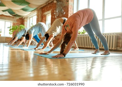 fitness, sport and healthy lifestyle concept - group of people doing yoga downward-facing dog pose on mats at studio - Powered by Shutterstock