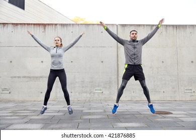 fitness, sport, people, exercising and lifestyle concept - happy man and woman doing jumping jack or star jump exercise outdoors - Shutterstock ID 421876885