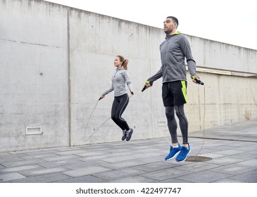 Fitness, Sport, People, Exercising And Lifestyle Concept - Man And Woman Skipping With Jump Rope Outdoors
