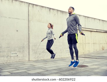 Fitness, Sport, People, Exercising And Lifestyle Concept - Man And Woman Skipping With Jump Rope Outdoors