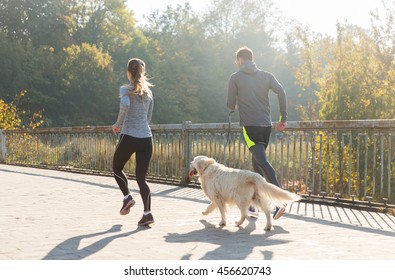 Fitness, Sport, People And Jogging Concept - Close Up Of Couple With Dog Running Outdoors