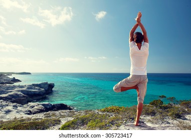 fitness, sport, people and lifestyle concept - young man making yoga exercises on beach from back - Powered by Shutterstock