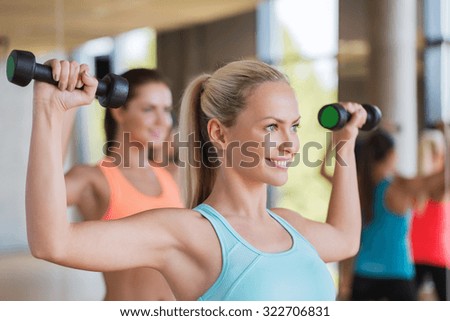 fitness, sport, people and lifestyle concept - group of women exercising with dumbbells in gym