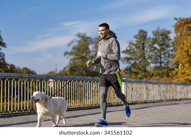 fitness, sport, people, pets and lifestyle concept - happy man with labrador retriever dog running outdoors