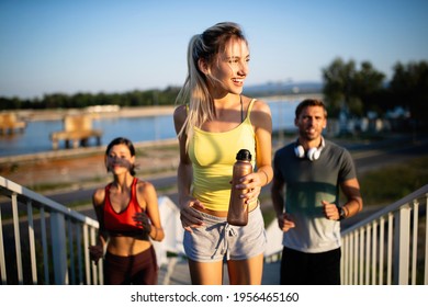 Fitness, sport, people and running concept. Happy fit friends running outdoors - Shutterstock ID 1956465160