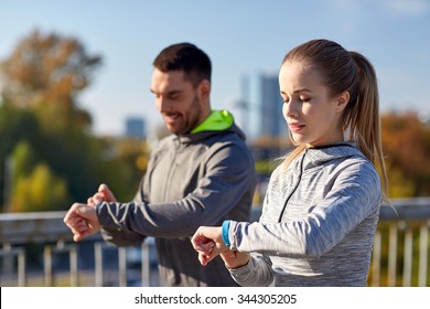 fitness, sport, people, technology and healthy lifestyle concept - smiling couple with heart-rate watch running over city highway bridge