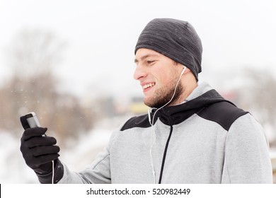 fitness, sport, people, technology and healthy lifestyle concept - happy smiling young man in earphones with smartphone listening to music on winter bridge - Powered by Shutterstock