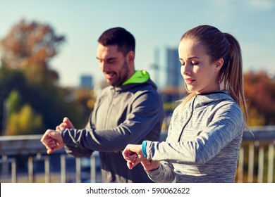 Fitness, Sport, People, Technology And Healthy Lifestyle Concept - Smiling Couple With Heart-rate Watch Running Over City Highway Bridge