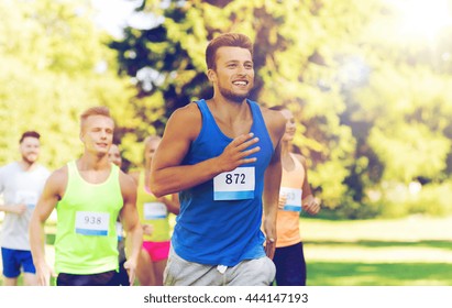 Fitness, Sport, Race And Healthy Lifestyle Concept - Group Of Happy Teenage Friends Or Sportsmen Running Marathon With Badge Numbers Outdoors