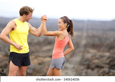 Fitness sport running couple celebrating cheerful and happy giving high five energetic and cheering. Runner couple having fun after trail cross-country running training. Asian woman, Caucasian man. - Powered by Shutterstock