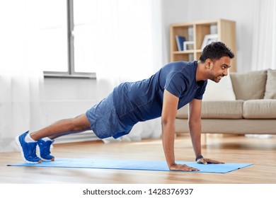 fitness, sport, training and concept - indian man doing push ups at home