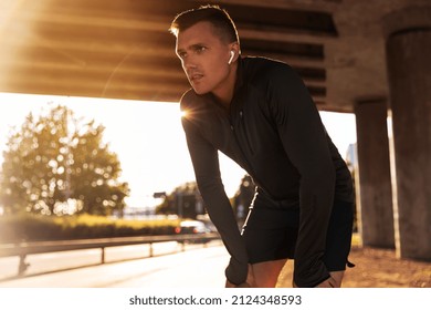 fitness, sport and training concept - tired young man in earphones doing sports outdoors - Powered by Shutterstock