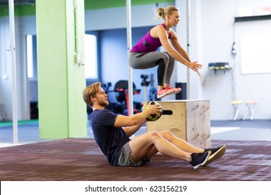 fitness, sport, training, exercising and people concept - woman and man with medicine ball doing curl ups and box jumps in gym