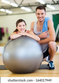 Fitness, Sport, Training, Gym And Lifestyle Concept - Two Smiling People With Fitness Ball In The Gym