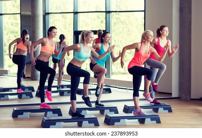 fitness, sport, training, gym and lifestyle concept - group of women working out with steppers in gym - Shutterstock ID 237893953