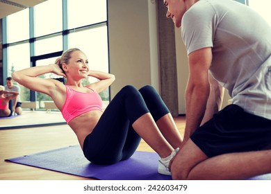 fitness, sport, training, gym and lifestyle concept - woman with personal trainer doing sit ups in gym - Powered by Shutterstock