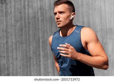 fitness, sport, training and lifestyle concept - young man in earphones running outdoors - Powered by Shutterstock