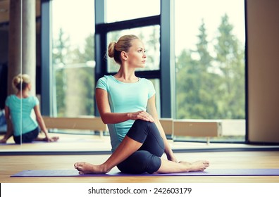 fitness, sport, training and lifestyle concept - smiling woman stretching leg on mat in gym - Powered by Shutterstock