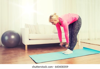 fitness, sport, training and lifestyle concept - smiling woman with dumbbells exercising and doing lean at home