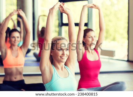 fitness, sport, training and lifestyle concept - group of smiling women stretching in gym
