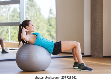 Fitness, Sport, Training And People Concept - Smiling Woman Flexing Abdominal Muscles With Exercise Ball In Gym