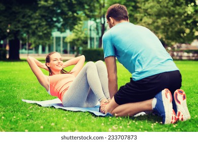 fitness, sport, training, teamwork and lifestyle concept - smiling woman with personal trainer doing exercises on mat outdoors - Powered by Shutterstock