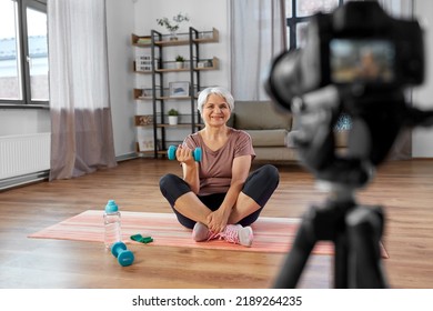 Fitness, Sport And Video Blogging Concept - Happy Senior Woman Or Blogger With Camera And Dumbbell Streaming Online Class At Home