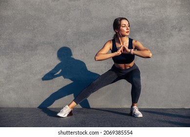 Fitness sport woman in sportswear, doing stretching exercises, doing yoga fitness exercises on the street, outdoor sports, on a gray wall background, urban style - Powered by Shutterstock