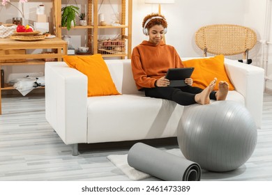 Fitness sport workout training at home. Healthy strong sporty athletic African girl in headphones use fitness app listen music hold tablet ready for yoga sports exercises training at home gym indoor - Powered by Shutterstock