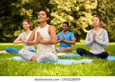 fitness, sport, yoga and healthy lifestyle concept - group of people meditating in lotus pose at summer park - Powered by Shutterstock