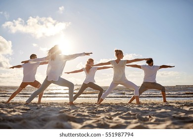 fitness, sport, yoga and healthy lifestyle concept - group of people making warrior pose on beach - Powered by Shutterstock