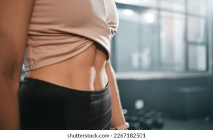 Fitness, stomach and woman in a gym for exercise, health or wellness for weightloss training. Sports, tummy tuck and closeup of a slim female athlete or model abs after a workout in a sport center.