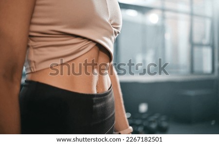 Fitness, stomach and woman in a gym for exercise, health or wellness for weightloss training. Sports, tummy tuck and closeup of a slim female athlete or model abs after a workout in a sport center.