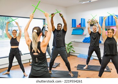 A Fitness Teachers with Green Drum Stick at the gym with a training group of peole - Powered by Shutterstock