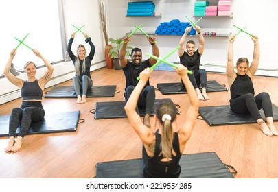 A Fitness Teachers with Green Drum Stick at the gym with a training group of peole - Powered by Shutterstock