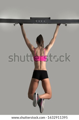 Fitness toes to bar woman pull ups 2 bars workout exercise at gym.Woman working out on cross bars in a gym hanging from extended arms during a fitness workout. back, rear view.