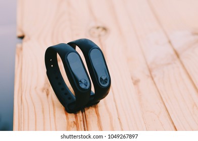 Fitness tracker. Isolated. Healthy lifestyle. Black fitness trackers lying on yellow wooden table. Healthcare, training, workout. Close-up photo. 
