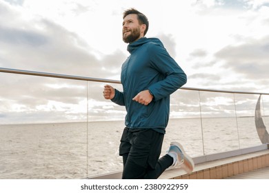 Fitness trainer active lifestyle for health. A man runs alone training in the cold. Athlete jogging in warm sportswear for autumn. - Powered by Shutterstock