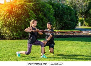 Fitness trainer and client in the park practice exercises with a rubber expander, tension bands. On the outdoor in the park. - Powered by Shutterstock