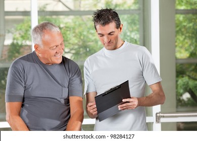 Fitness Trainer Explaining Training Plan To Senior Man In Gym