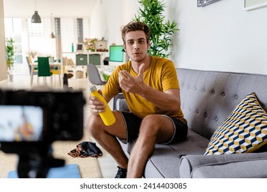 Fitness trainer live streaming fitness session while sitting on sofa at home - Powered by Shutterstock