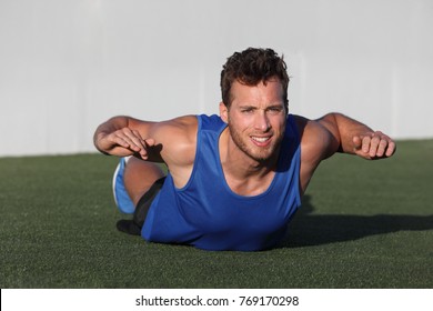 Fitness Training Back Fat Exercise Fit Man Doing Superman Variation Of Lower Body Workout. Strong Athlete Working Out Outdoors In Park Grass. Lower Body Back Lumbar Muscles Strengthening Exercises.