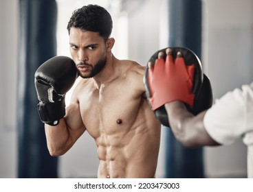 Fitness, training and a man boxing in gym with personal trainer and sparring pads. Health, motivation and exercise, boxer throwing a punch. Fight, muscle and workout with sports gloves in mma studio. - Powered by Shutterstock