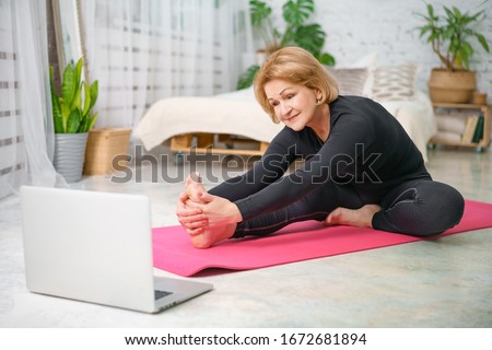 Fitness training online, senior woman at home with laptop.