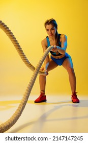 Fitness Training. Portrait Of Young Sportive Girl Workout With Sports Ropes Isolated On Yellow Studio Background. Female Sport, Action, Motion, Beauty And Health Lifestyle Concept. Copy Space For Ad