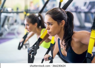Fitness trx suspension straps training exercises women doing push-ups, working with own weith at gym
