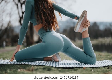 Fitness and well-being concept with a woman stretching her leg on a yoga mat in a park, enjoying a sunny outdoor workout. - Powered by Shutterstock