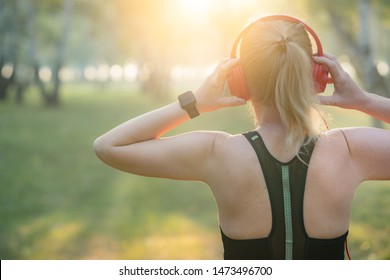 Fitness woman adjusting wireless headphones before starting jogging. Healthy lifestyle concept. - Powered by Shutterstock