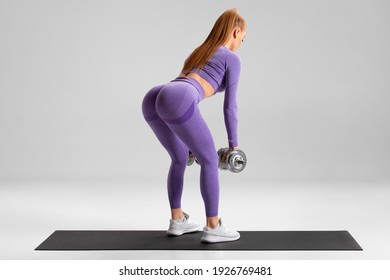 Fitness woman doing deadlift exercise for glutes on gray background. Athletic girl working out with dumbbells